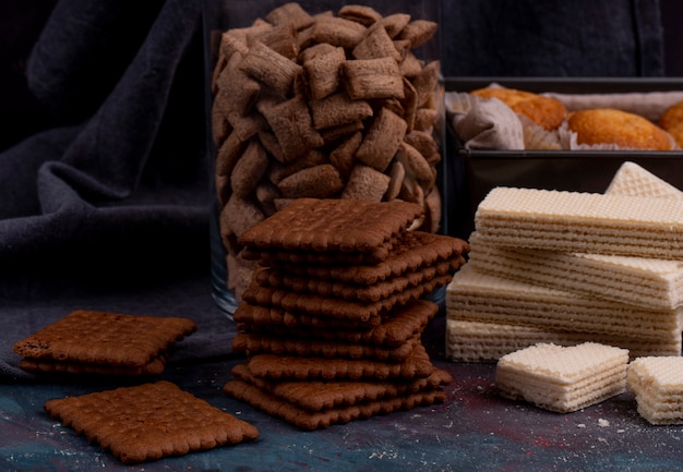 Foto gratuita vista laterale di biscotti al cioccolato e cialde croccanti su oscurità