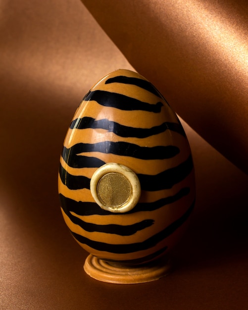 Free photo side view chocolate egg in tiger color on stand
