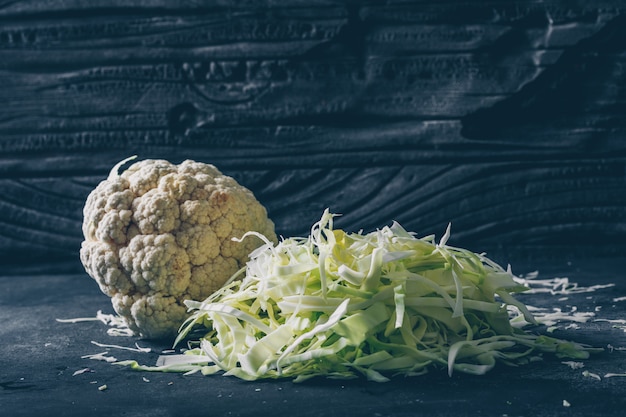 Free photo side view chopped cabbage with cauliflower on dark background. horizontal