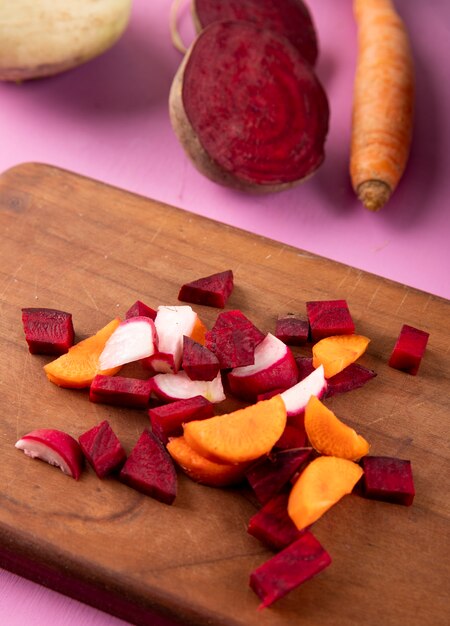 Side view chopped carrots with beetroot and radish on the board