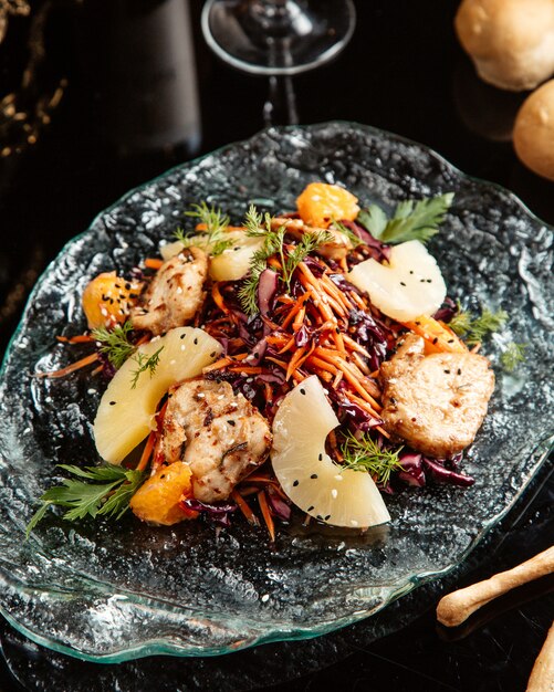 Side view of chopped vegetable salad with chicken and pineapple on a plate on the table