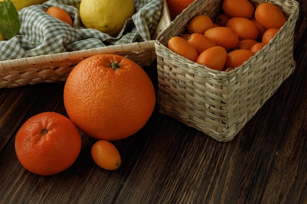 Side view of citrus fruits as orange tangerine kumquat basket of lemon on wooden background