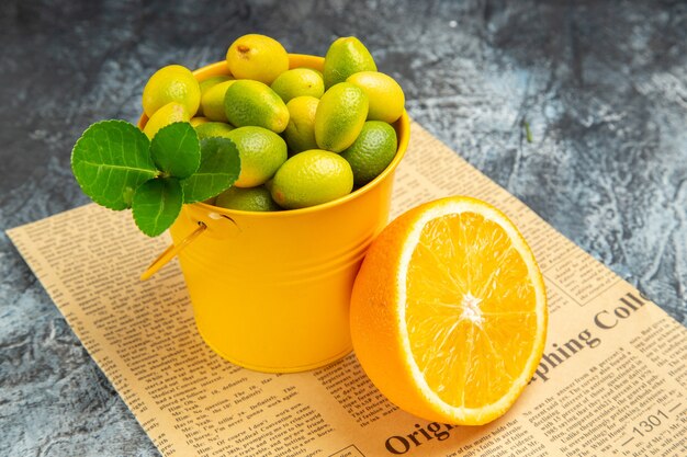 灰色の背景のヒメタチバナとオレンジ色のストックフォトの新聞に柑橘系の果物の側面図