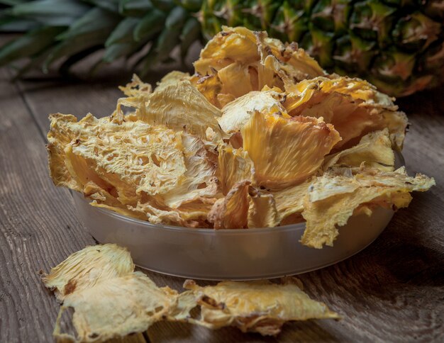 Side view close-up dried pineapple and fresh pineapple on wooden table