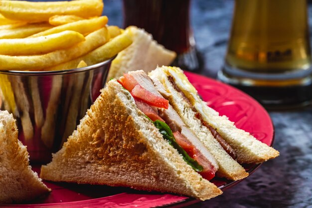 Side view club sandwich with grilled chicken tomato lettuce and french fries on the table