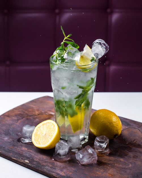Side view of cocktail mojito with ice and lemon on a wooden board