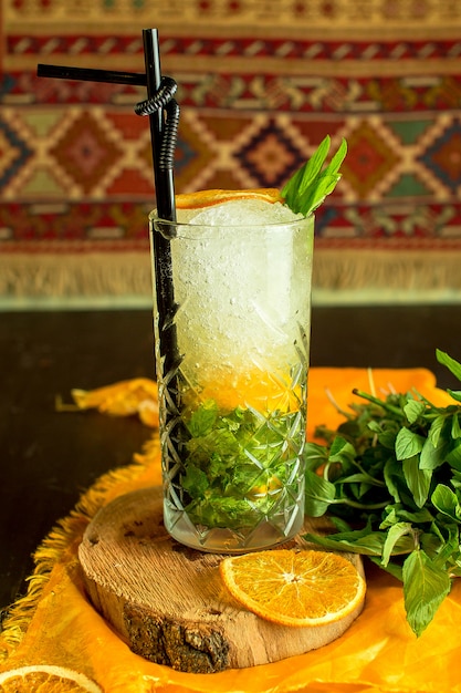 Вид сбоку коктейль Мохито со льдом и апельсином в стакане