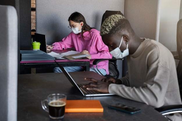 Free photo side view colleagues wearing face masks