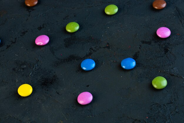 Side view of colorful candies scattered on black