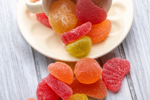 Side view of colorful marmalade candies scattered on rustic