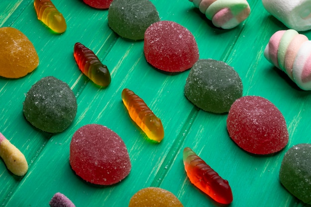 Free photo side view of colorful marmalade jelly candies on green wood