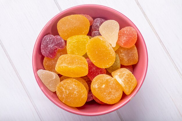 Side view of colorful tasty marmalade candies in a bowl on rustic