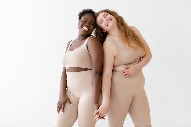 Side view of confident smiley women posing while wearing a body shaper