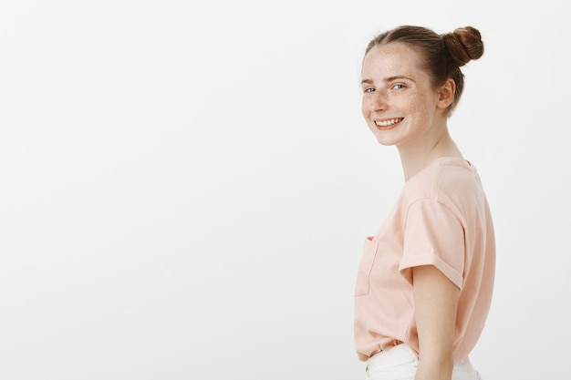 Side view of confident teenage girl posing against the white wall