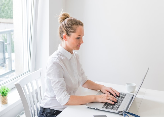 Side view of confident young woman using laptop