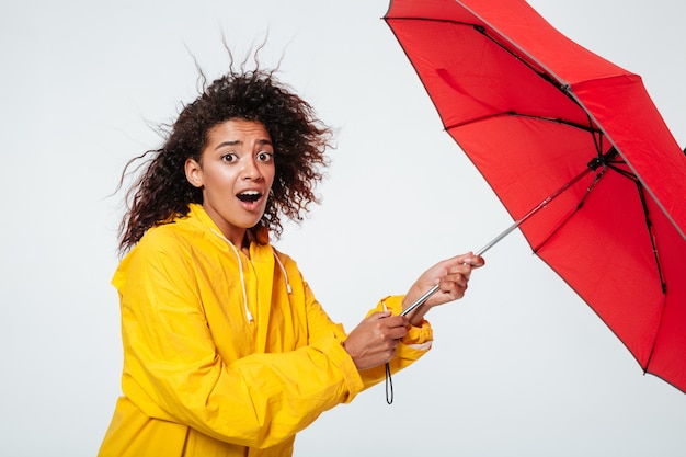 Side view of confused surprised african woman in raincoat