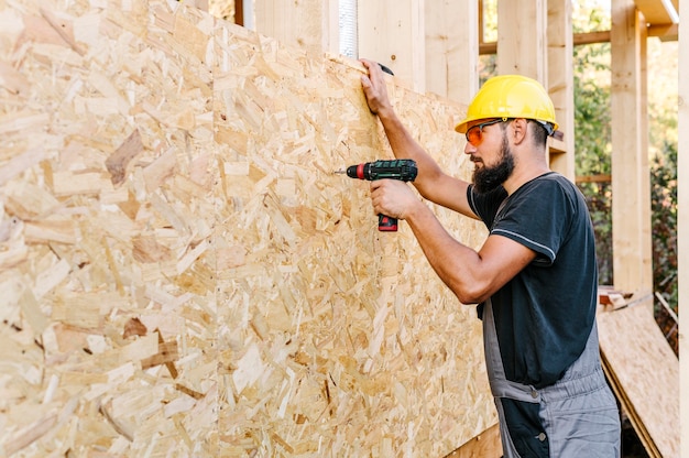 Side view of construction worker drilling in plywood with copy space