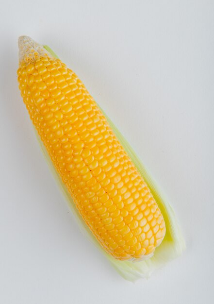 Side view of cooked corn on white surface