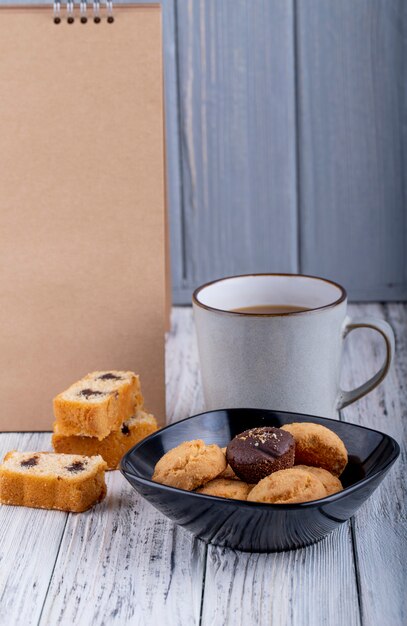 Side view of cookies on a bowl and a cup of tea on rustic