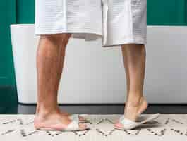 Free photo side view of couple in bathrobes with slippers