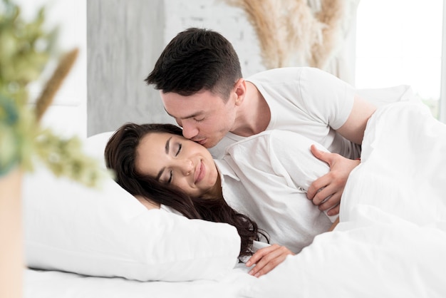 Side view of couple in bed being romantic