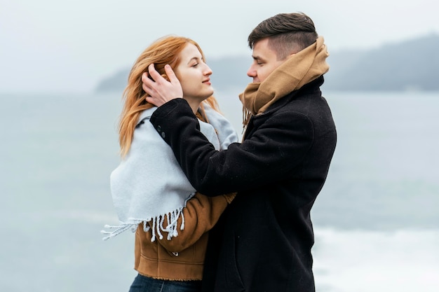 Side view of couple by the lake during winter