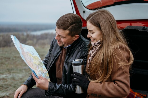 車のトランクの地図をチェックするカップルの側面図