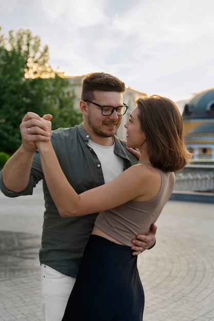 Free photo side view couple dancing outdoors