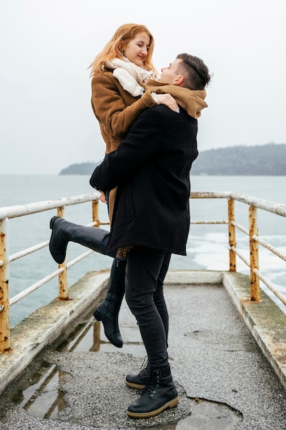 Side view of couple embraced by the lake during winter