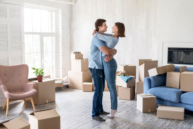 Side view of couple embraced at home among boxes on moving out day