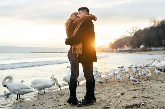 Side view of couple embracing on the beach in winter