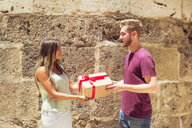 Side view of a couple holding gift against wall