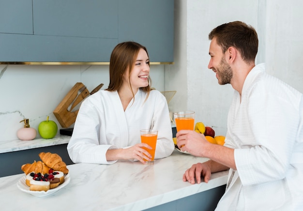 Side view of couple holding glasses of juice