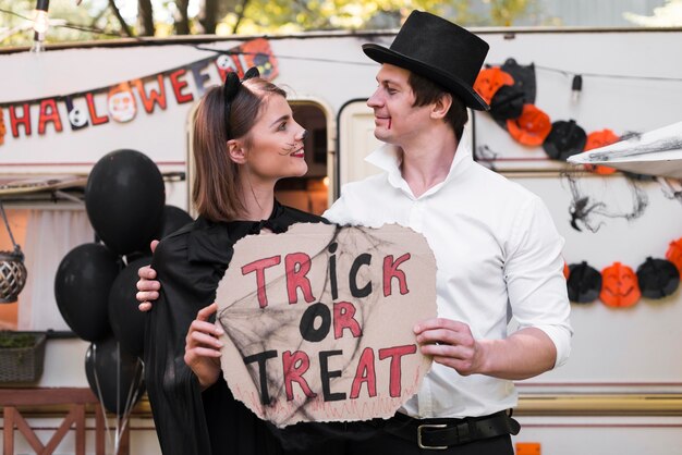 Side view couple holding halloween sign
