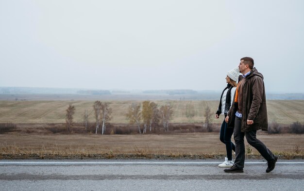 Side view of couple holding hands on the road