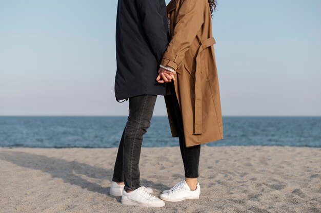 Side view couple holding hands at seaside