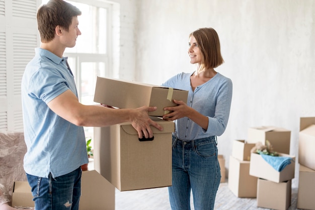 Side view of couple holding moving out boxes