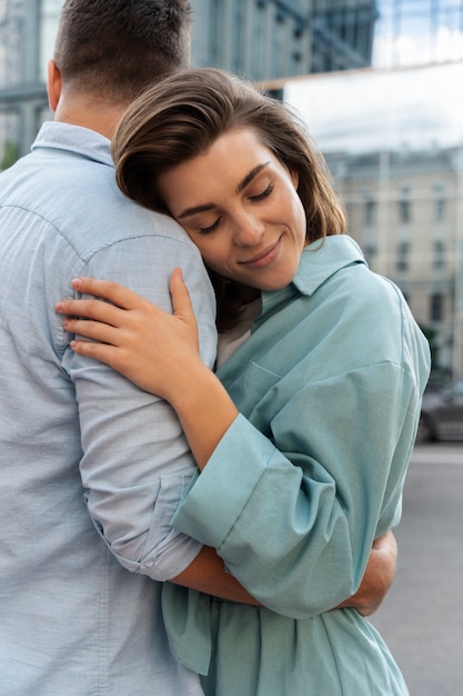 Free photo side view couple hugging outdoors