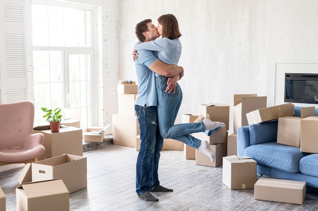 Free photo side view of couple kissing at home on moving out day