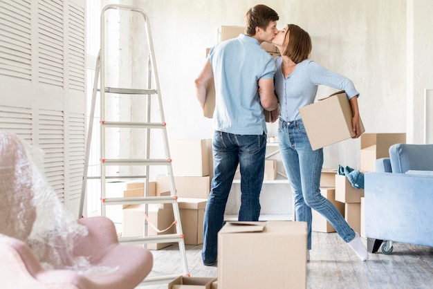 Side view of couple kissing while packing to move out