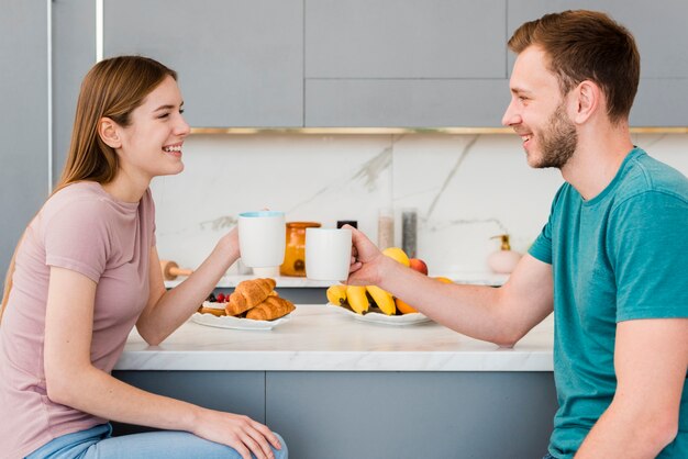 Side view of couple in the kitchen holding cups