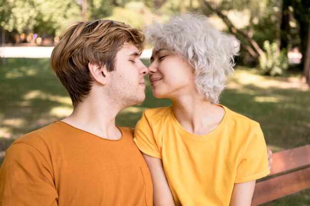 公園でキスのために傾いているカップルの側面図