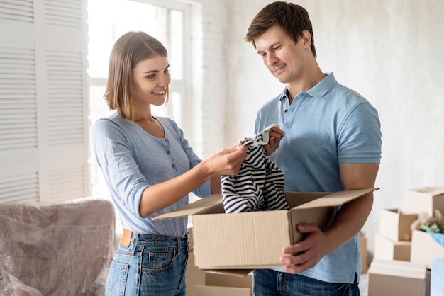 Free photo side view of couple packing clothes to move house