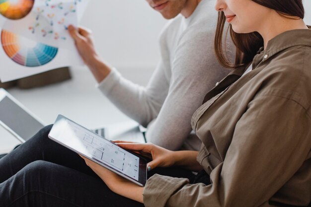 Side view of couple planning to redecorate the house using tablet and paint palette