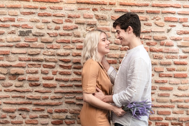 Free photo side view of couple posing with lavender flowers and copy space