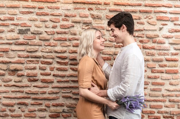 Side view of couple posing with lavender flowers and copy space