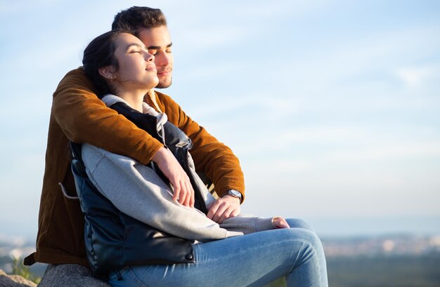 Side view of couple resting after hiking in autumn. Man and woman in casual clothes sitting at peak. Nature, activity, hobby concept