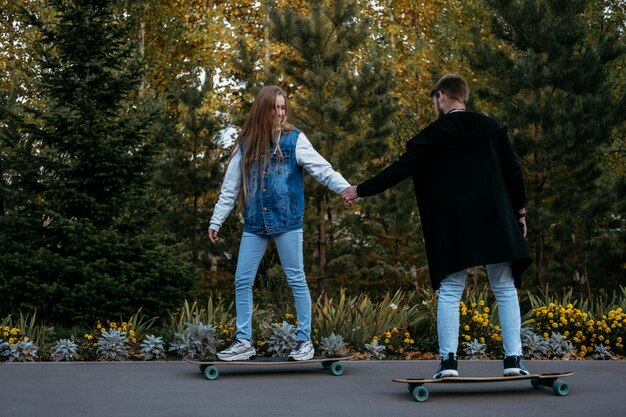 Side view of couple skateboarding outdoors in the park