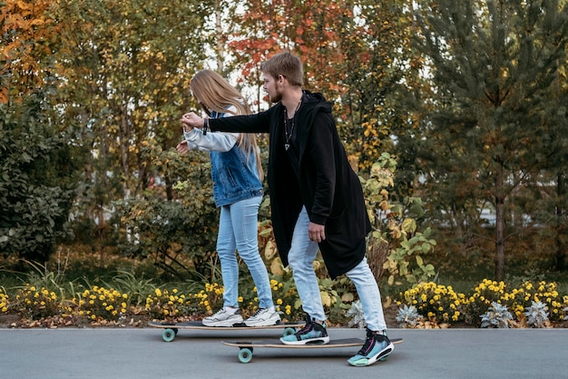 Side view of couple skateboarding together in the park