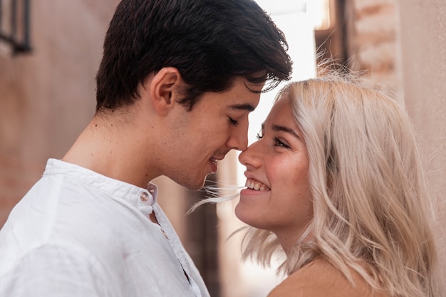 Free photo side view of couple smiling and going in for a kiss